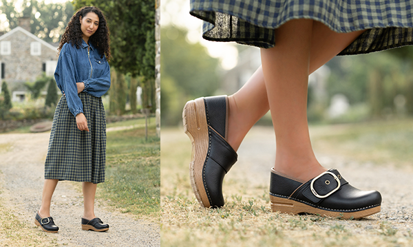 Woman standing in field wearing black Dansko clogs with large gold buckle