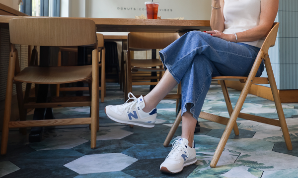 Woman wearing New Balance 574 lifestyle sneakers in a coffee shop