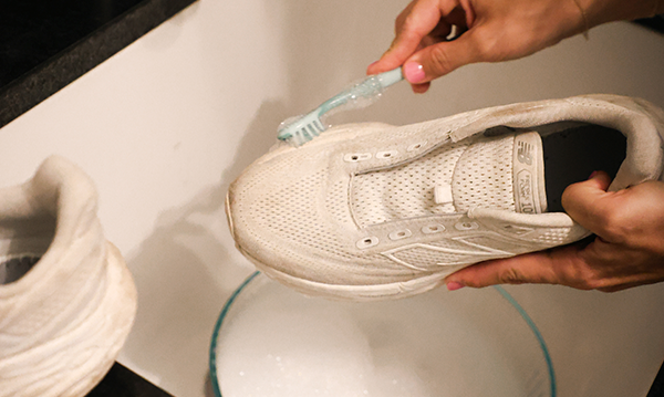 A pair of running shoes being scrubbed with a toothbrush