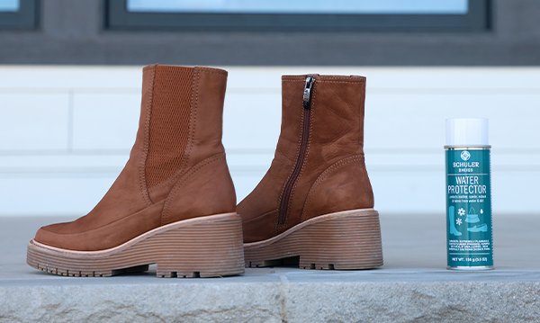 A pair of boots sitting next to a bottle of water protector spray