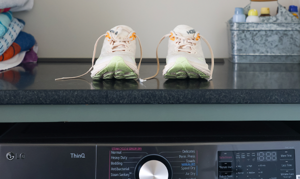 A pair of running shoes sitting on top of a washing machine