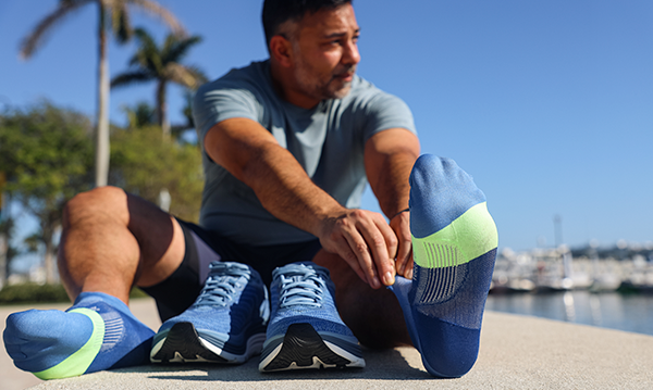Man stretching next to a pair of Hoka running shoes