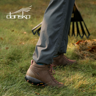 Woman raking leaves in yard in Dansko Perrin boots 
