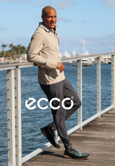 Man leaning against railing wearing Ecco sneakers