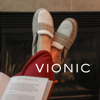 Woman crossing legs reading a book wearing Vionic Gemma II Slippers