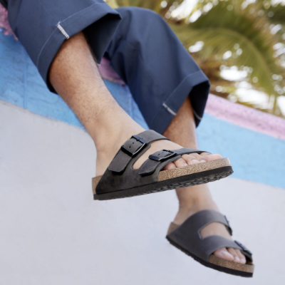 Man sitting on side of wall with legs hanging off