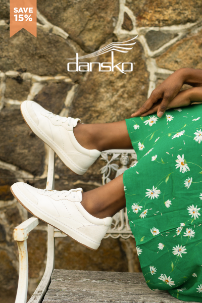 Woman sitting on bench with feet in the air, wearing Dansko sneakers