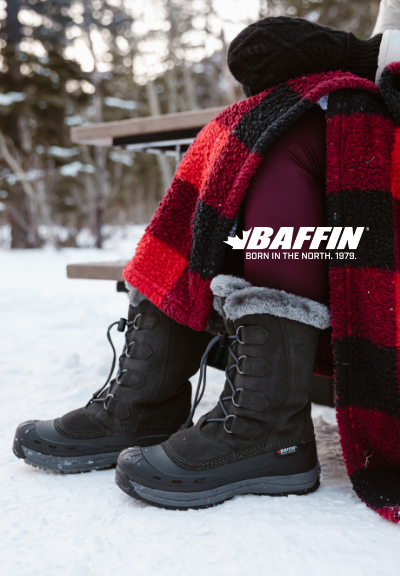 Woman sitting at picnic table in snow wearing Baffin winter boots