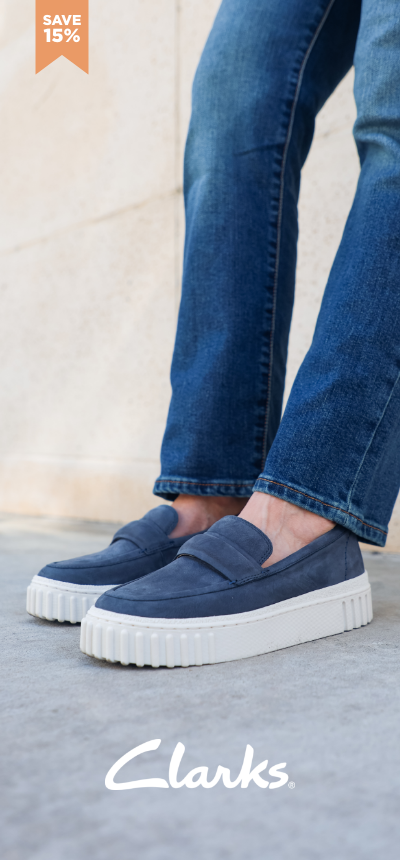 Woman leaning against wall wearing Clarks