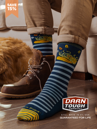 Man sitting on couch putting Darn Tough socks on 