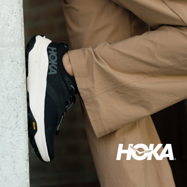 Woman resting foot against wall wearing Hoka transport's