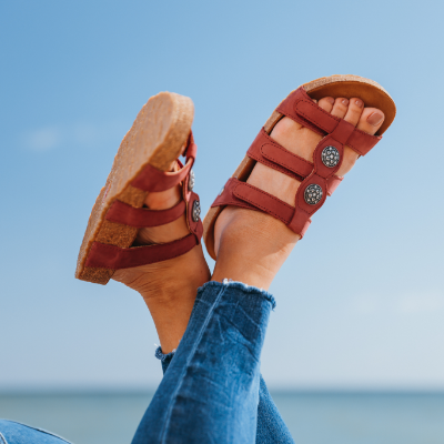 Woman raising feet in the air by the ocean
