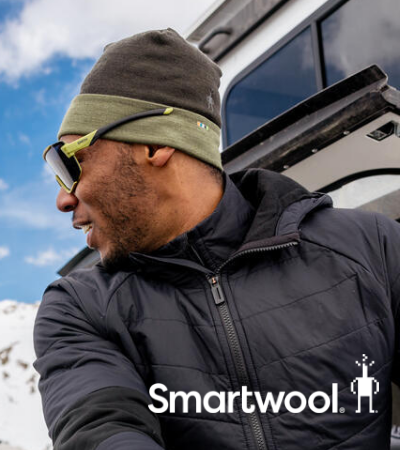 Man waxing snowboard in Smartwool hat