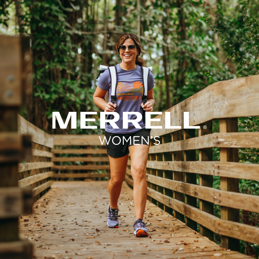 Woman walking on walkway through woods