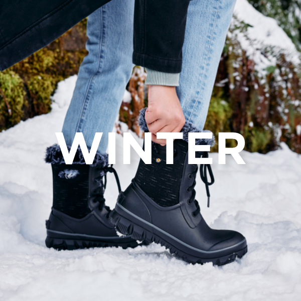 Woman putting on boot in snow