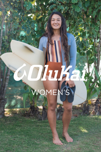 Woman standing with surfboard and shoes in hand