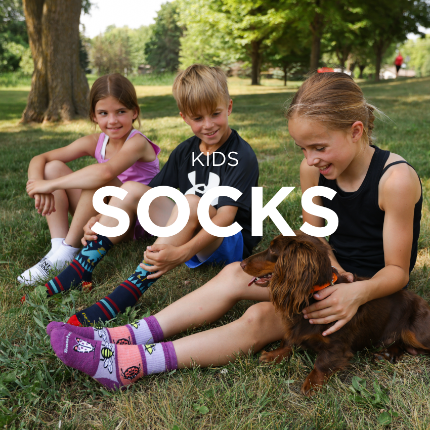 3 kids sitting in grass playing with dog