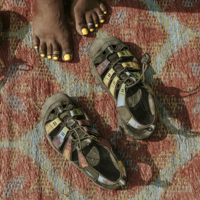 Woman standing next to shoes on outdoor rug 