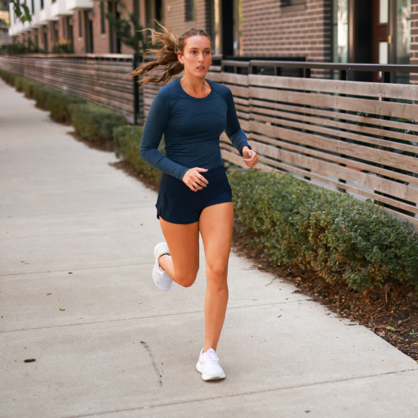 Woman running on sidewalk next to apartments