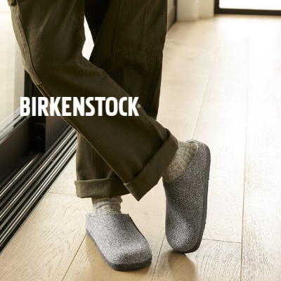 Man leaning against sliding glass doors wearing Birkenstock Zermatt Shearling Slippers