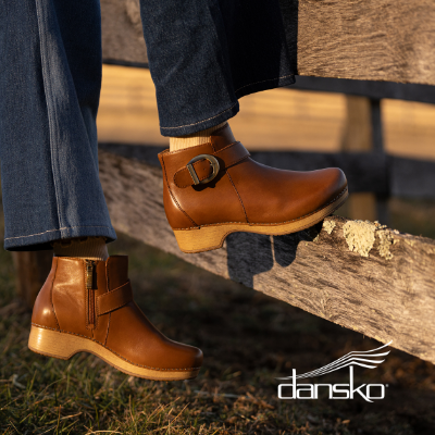 Woman standing on fence post in Dansko Brennan boots