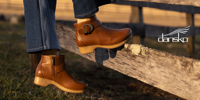 Woman standing on fence post in Dansko Brennan boots