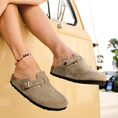 Woman wearing Birkenstock Boston clogs with her feet hanging out the window of a car