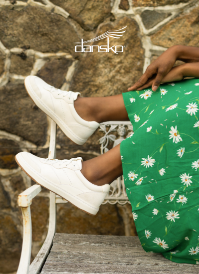 Woman wearing Dansko sneakers sitting on bench