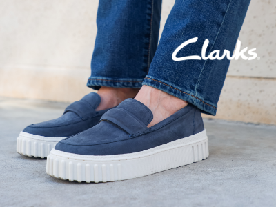 Woman leaning against wall with Clarks shoes on 