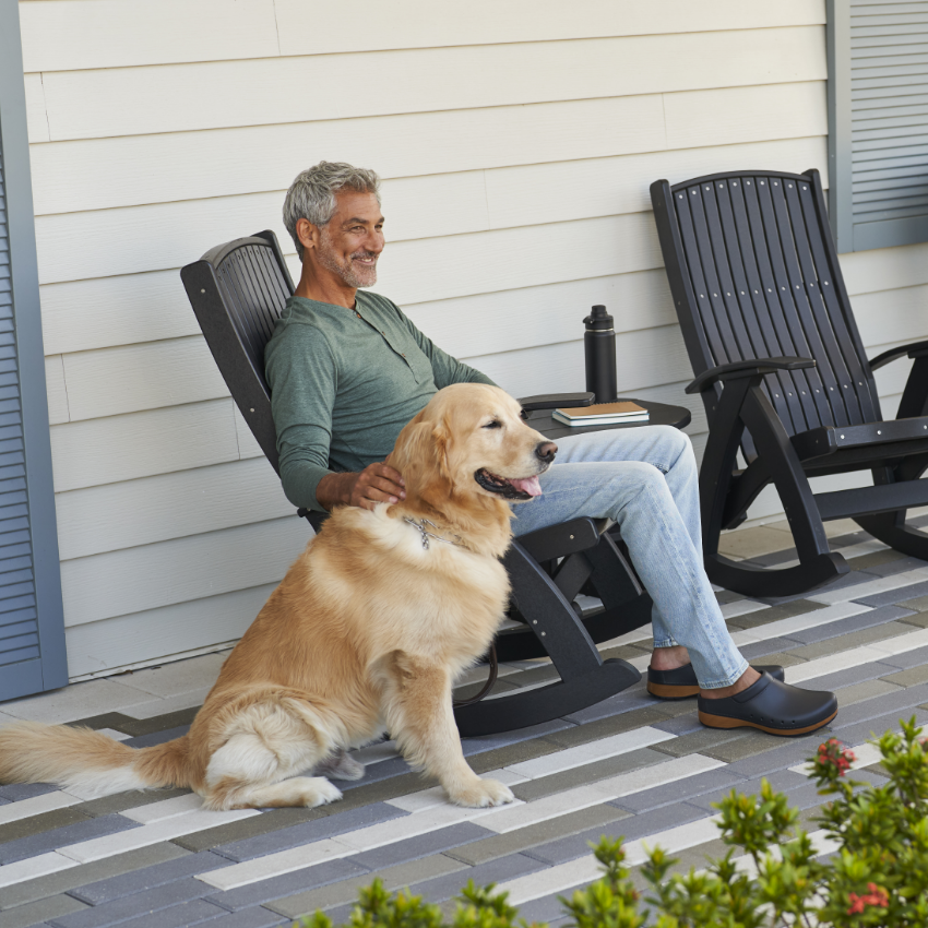 Man sitting in chair with dog in Dansko shoes 