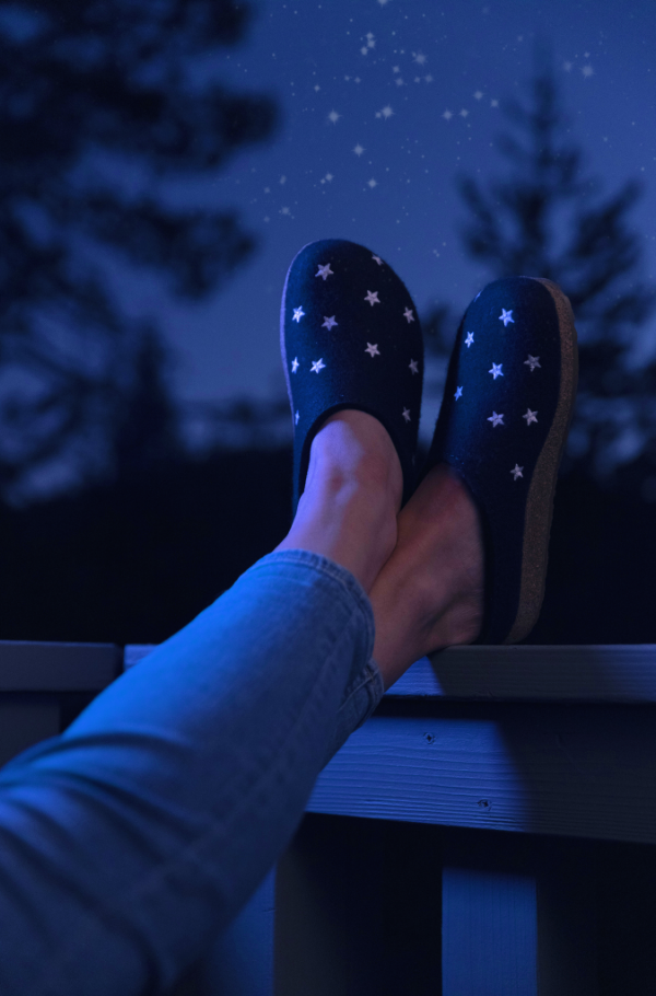 Woman sitting in chair resting feet on balcony railing 