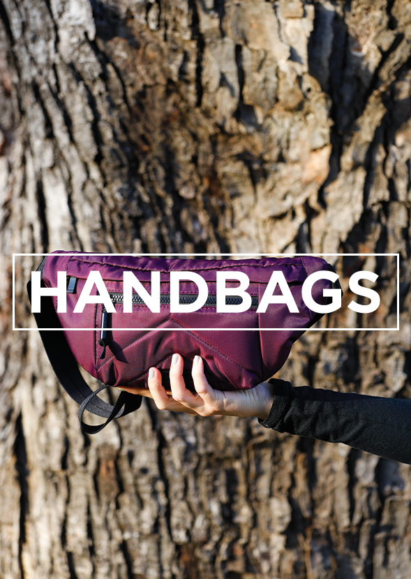 human holding a handbag in front of a tree trunk