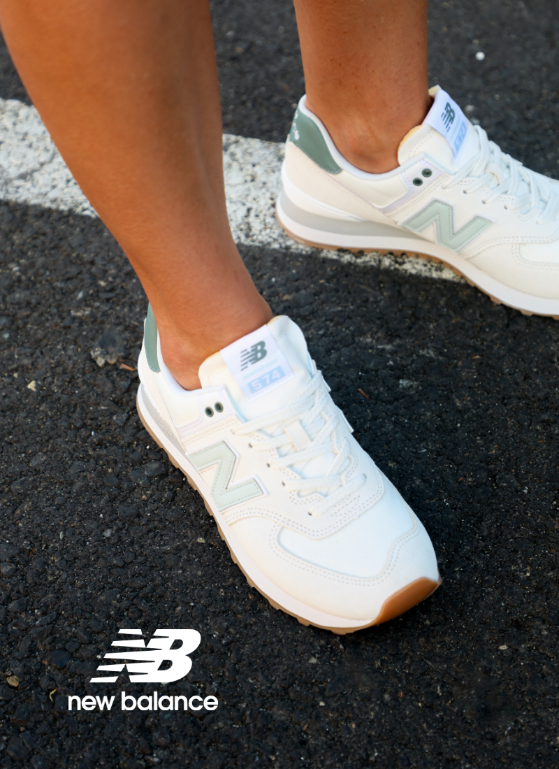 Woman standing on pavement wearing New Balance 574 sneakers