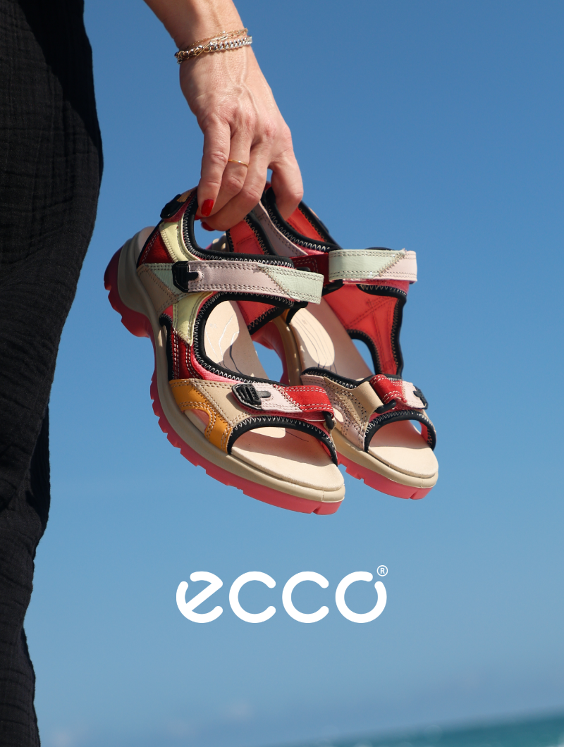 Woman carrying Ecco sandals on beach