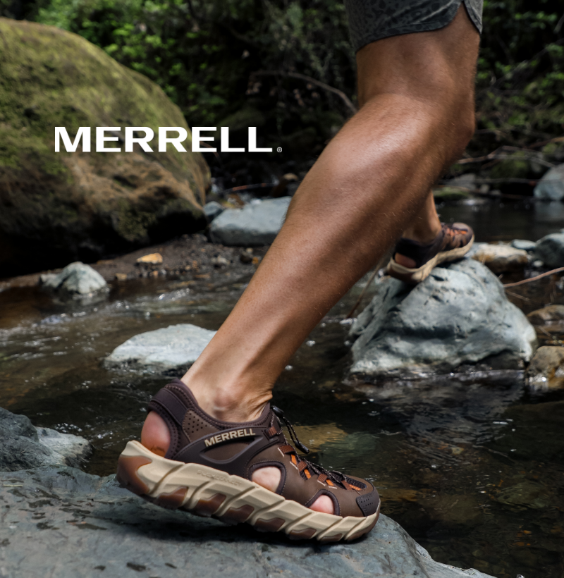 Man hoping across river in Merrell sandals