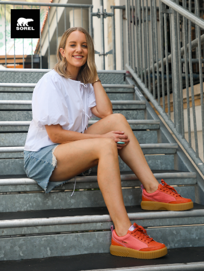 Woman sitting on stairs wearing Sorel sneakers