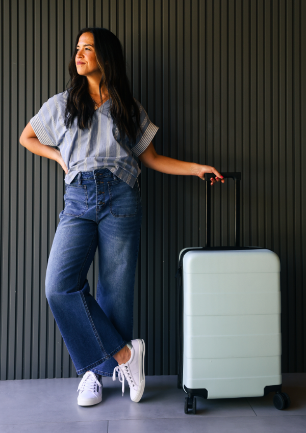 Woman wearing Taos sneakers carrying suitcase
